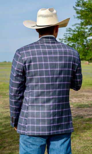 Person wearing a plaid jacket and cowboy hat in an outdoor setting