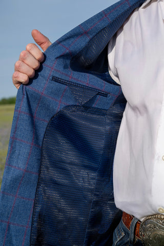 Person wearing a blue checkered jacket with a white shirt outdoors