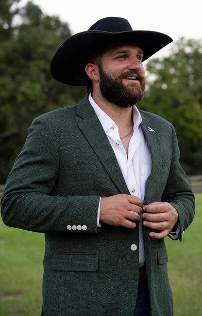 Man wearing a green suit and black cowboy hat outdoors