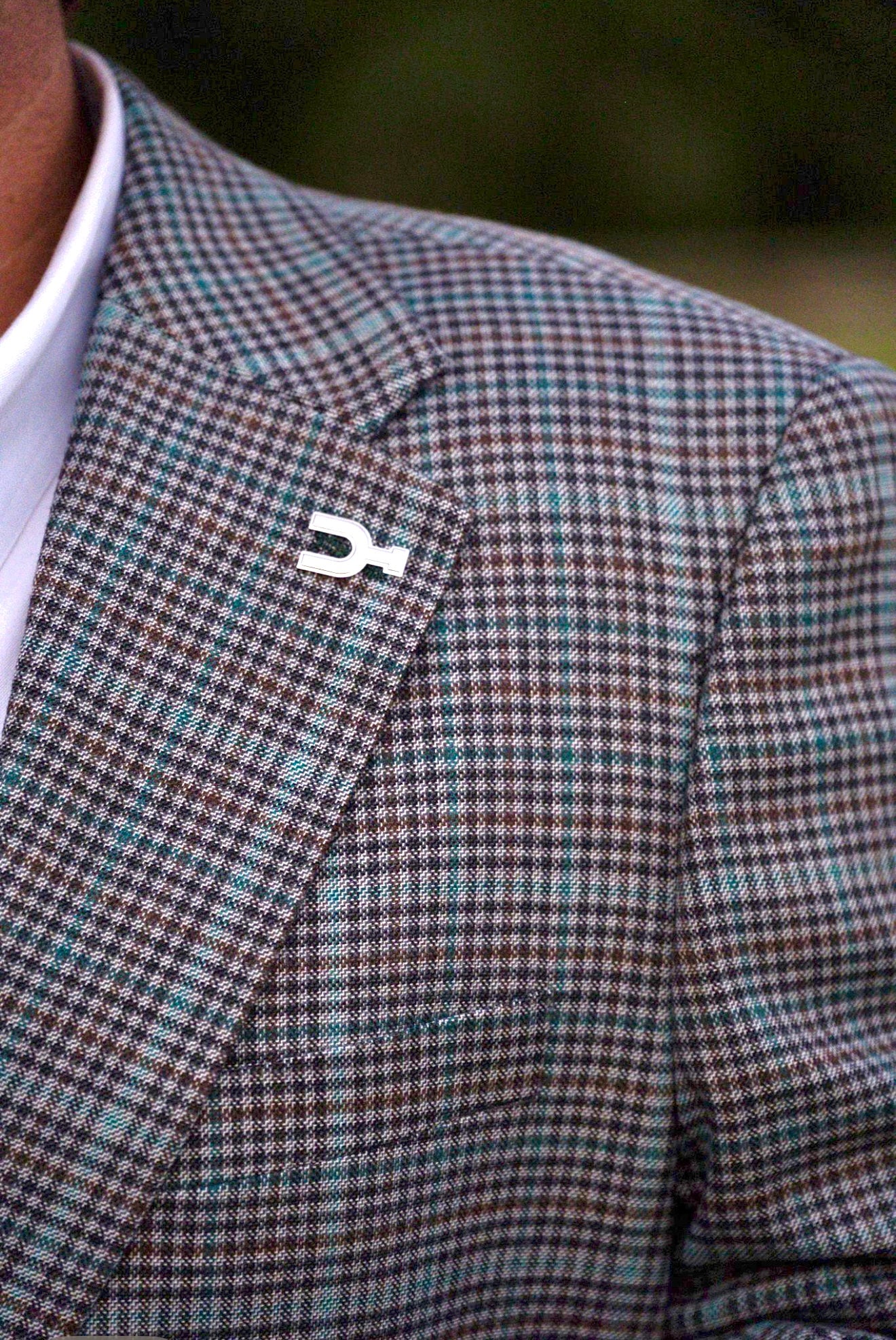 Checkered blazer with a distinctive lapel pin on a blurred background