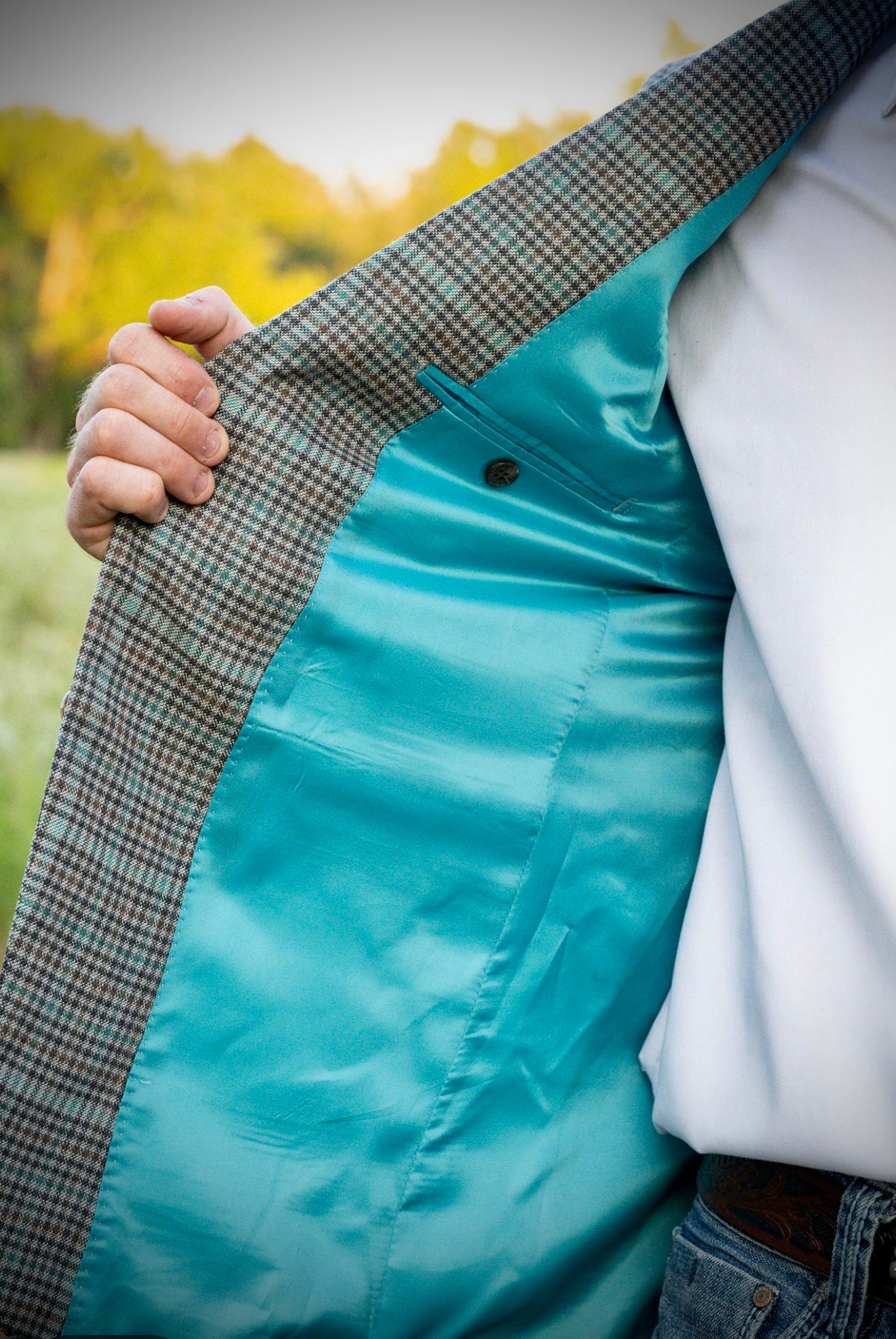 Close-up of a person wearing a turquoise jacket with a plaid pattern, outdoors.